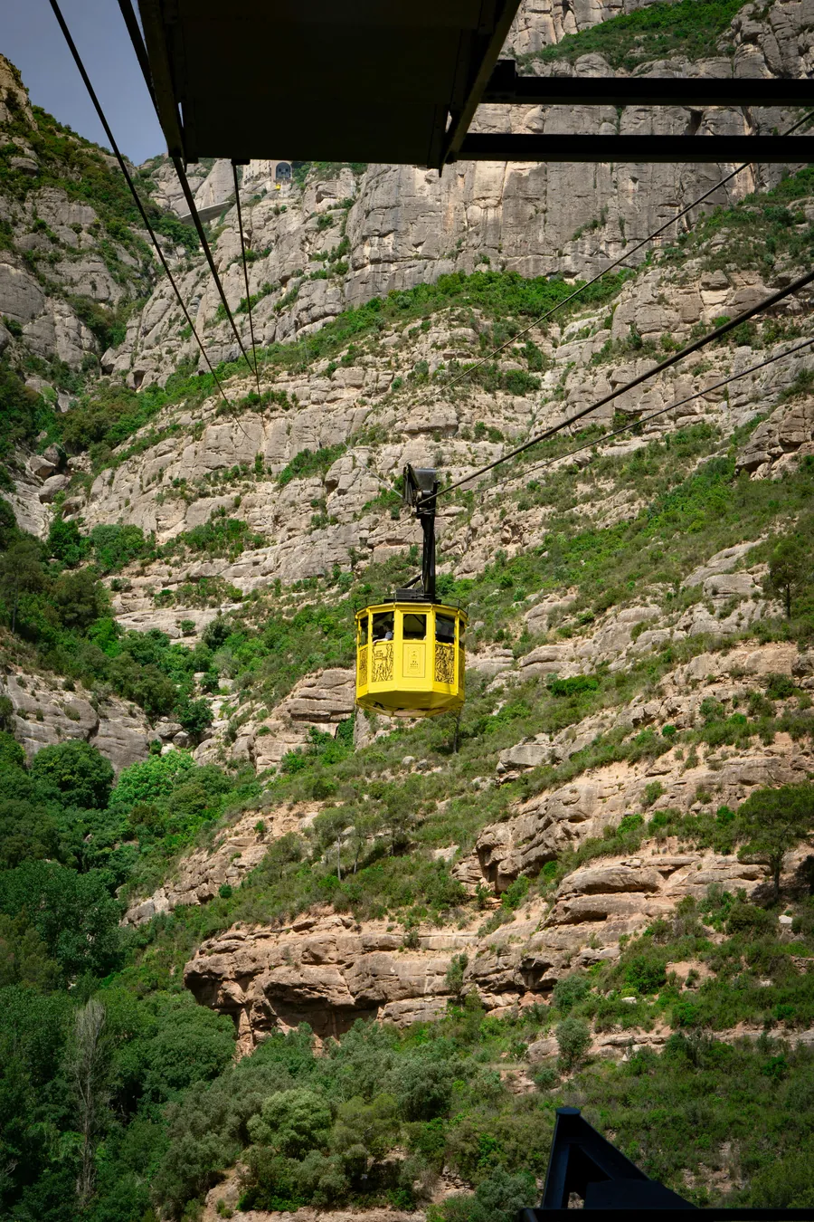 Yellow Aeri de Montserrat cable car against sandstone cliffs